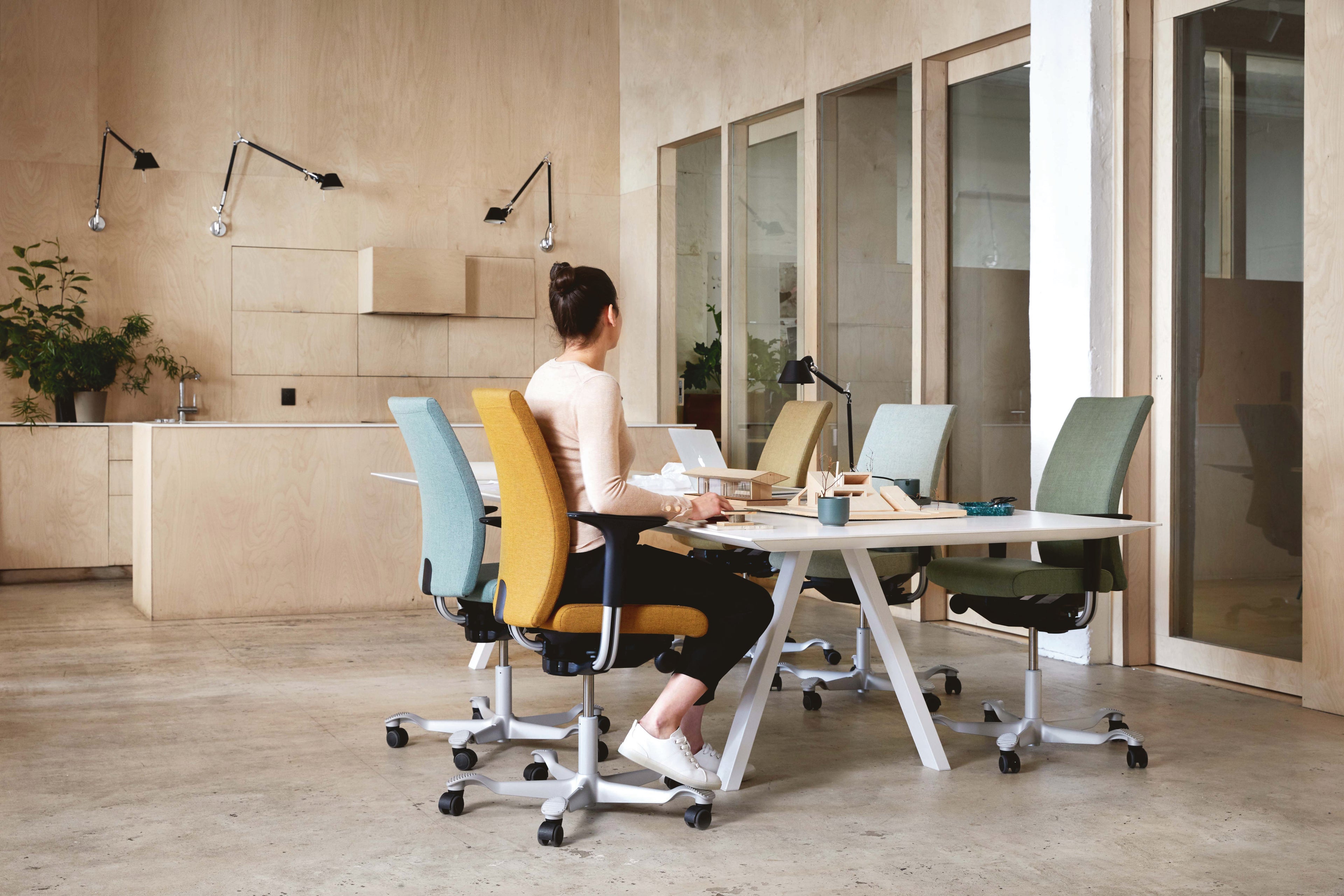 Person sitting at a modern office desk, on a HAG Creed ergonomic office chair